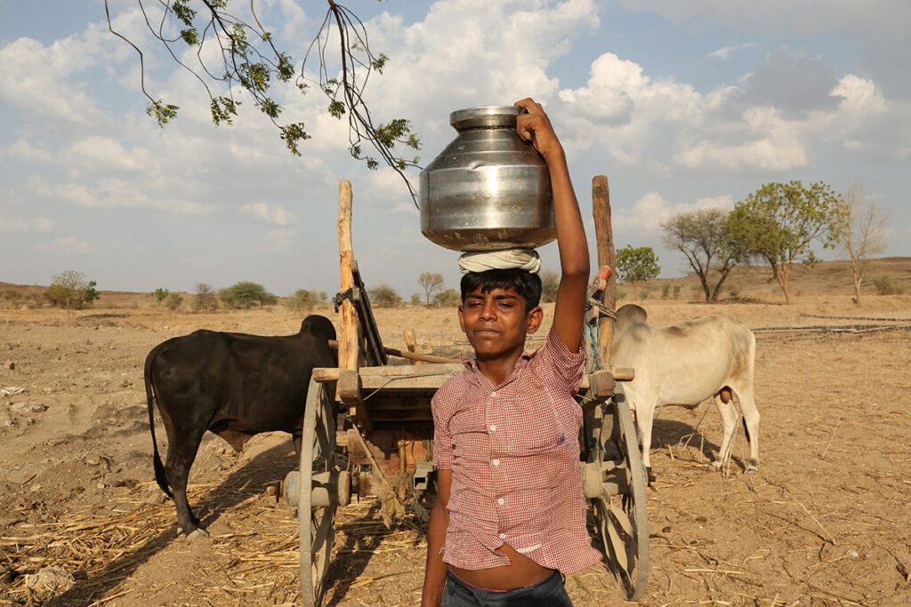 Indiase jongen vervoert drinkwater op hoofd